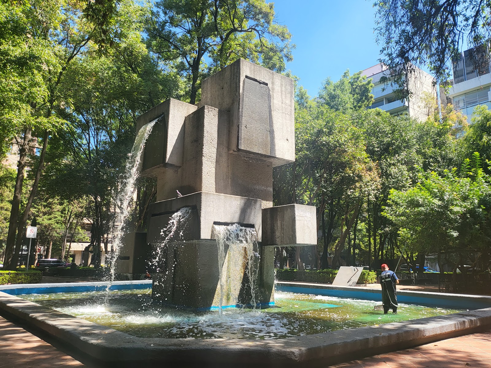 La fuente brutalista y las bancas a la sombra